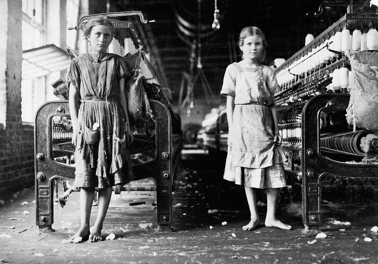 1911 photograph of spinners working among rows of machinery on a cotton mill floor